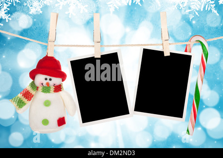 Fustellato cornici fotografiche e pupazzo appeso sul stendibiancheria blu su sfondo di Natale Foto Stock