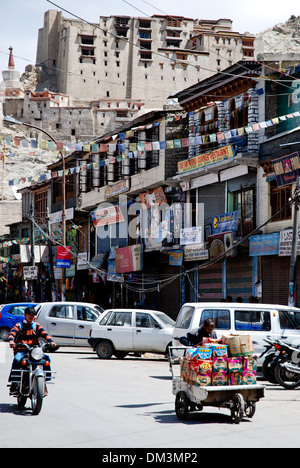 Ladakh, India - 12 Luglio 2009: Street View di Leh con la consegna di un uomo e di una motorscyclist. Bandiere di preghiera e il Leh Palace Foto Stock