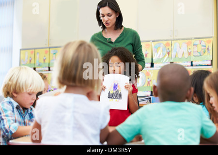 Pupilla elementari che mostra il disegno ai compagni in aula Foto Stock
