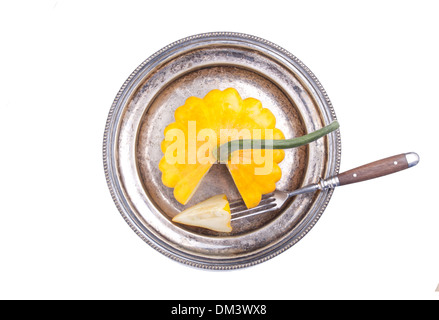 Pattypan giallo sulla vecchia piastra di argento con la forcella su sfondo bianco Foto Stock