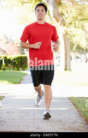 Runner maschio esercita sulla strada suburbana Foto Stock