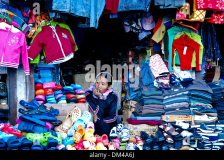 Ladakh, India - 16 Luglio 2009: una donna si siede in attesa per il cliente successivo in un colorato negozio di abbigliamento in Leh. Foto Stock