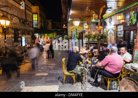 Gli uomini di fumare narghilè outdoor presso Al Nawfara coffeehouse, Damasco, Siria Foto Stock