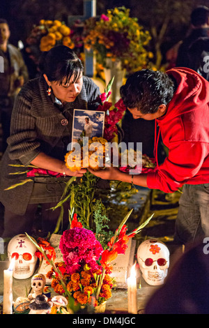 I membri della famiglia accendono le candele in onore del morto a San Felipe de Aqua cimitero durante il Giorno dei Morti Festival noto in spagnolo come Día de Muertos il 2 novembre 2013 a Oaxaca, Messico. Foto Stock