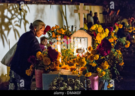I membri della famiglia accendono le candele in onore del morto a San Felipe de Aqua cimitero durante il Giorno dei Morti Festival noto in spagnolo come Día de Muertos il 2 novembre 2013 a Oaxaca, Messico. Foto Stock