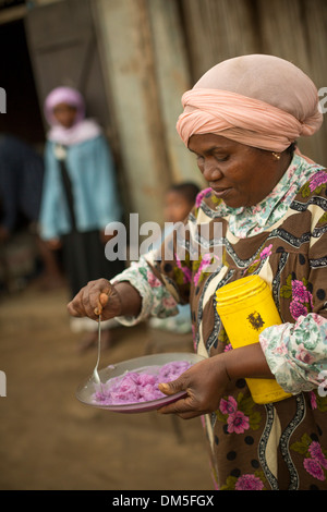 Una donna serve piatti freschi patate nella regione di Atsinanana, Madagascar. Foto Stock