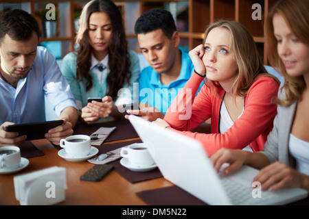 Ritratto di adolescenti amici utilizzando gadget moderni mentre è seduto in cafe Foto Stock