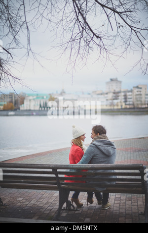Immagine di affettuosa coppia giovane seduto sul banco in posizione di parcheggio Foto Stock