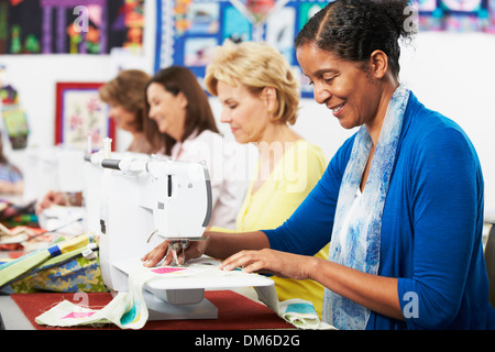 Un gruppo di donne che utilizzano macchine elettriche per cucire in classe Foto Stock