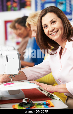 Un gruppo di donne che utilizzano macchine elettriche per cucire in classe Foto Stock