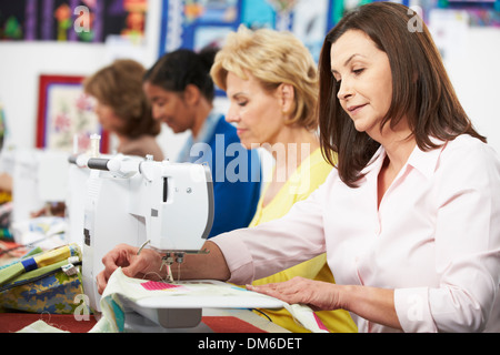 Un gruppo di donne che utilizzano macchine elettriche per cucire in classe Foto Stock