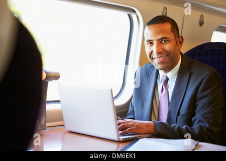 Imprenditore il pendolarismo per lavorare sul treno e utilizzando computer portatile Foto Stock