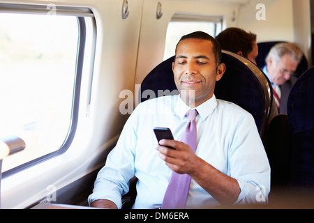 Imprenditore il pendolarismo per lavorare sul treno usando il telefono cellulare Foto Stock