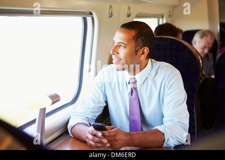 Imprenditore il pendolarismo per lavorare sul treno usando il telefono cellulare Foto Stock