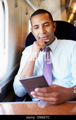 Imprenditore il pendolarismo SULLA LETTURA DEL TRENO E PRENOTA Foto Stock