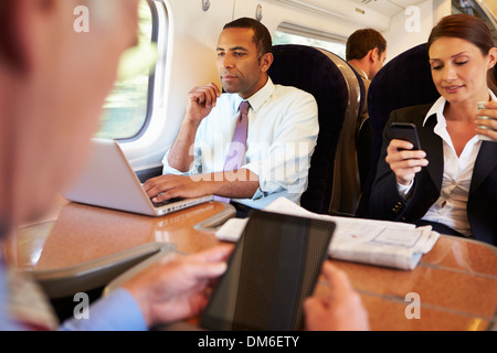 Gli imprenditori sul treno usando dispositivi digitali Foto Stock