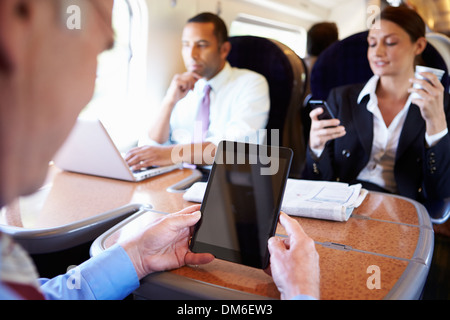 Gli imprenditori sul treno usando dispositivi digitali Foto Stock