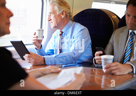 Imprenditore rilassante sul treno con la tazza di caffè Foto Stock