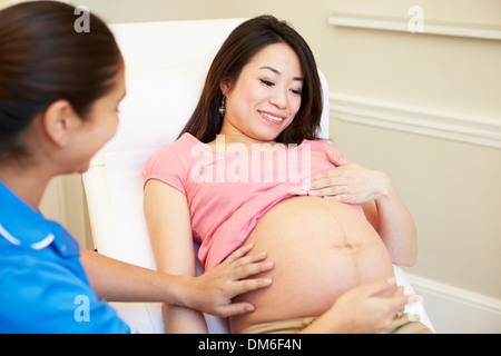 Donna incinta essendo dato Ante Natal controllare da un infermiere Foto Stock