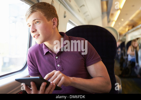 Giovane uomo leggere e prenotare il viaggio in treno Foto Stock