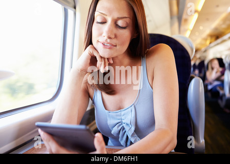 La donna e la lettura di un libro sul treno Foto Stock
