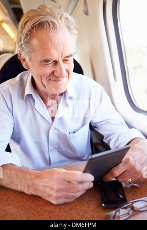 Senior uomo leggere e prenotare il viaggio in treno Foto Stock