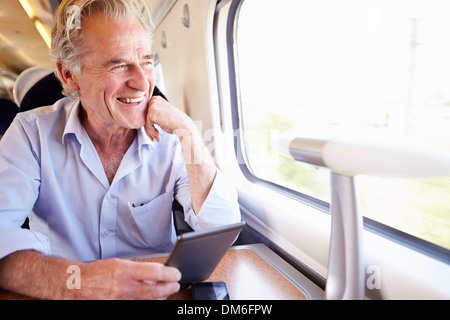 Senior uomo leggere e prenotare il viaggio in treno Foto Stock