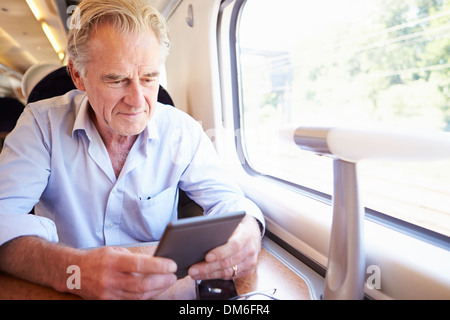 Senior uomo leggere e prenotare il viaggio in treno Foto Stock