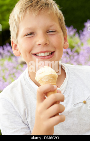 Giovane ragazzo a mangiare il gelato all'aperto Foto Stock
