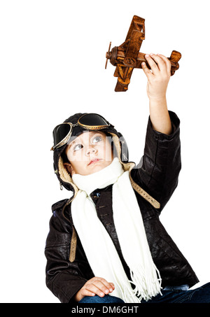 Felice ragazzo carino vestita come una guerra mondiale II riproduzione pilota con legno giocattolo aereo su sfondo bianco.look vintage Foto Stock