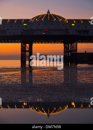 Il Brighton Pier tramonto a bassa marea, con il Molo Ovest attraverso l'arco Foto Stock
