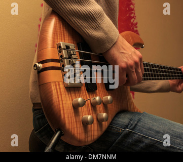 Uomo seduto e suonare una chitarra basso (serie con lo stesso modello disponibile). Foto Stock