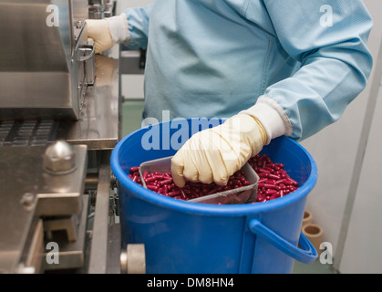 Produzione farmaceutica con la macchina blisteratrice e mano umana in guanti Foto Stock