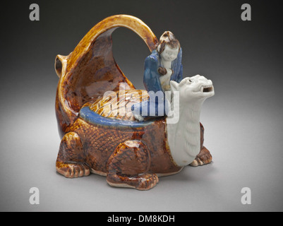 Questa nave Sake, progettata sotto forma di Urashima Taro a cavallo di una tartaruga dalla coda lunga, è un notevole esempio di arte ceramica giapponese. Fonde la narrazione culturale con il design funzionale, riflettendo temi del folklore giapponese. Foto Stock