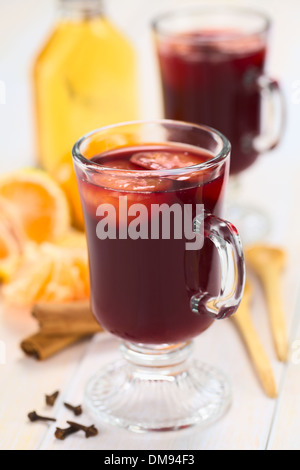 Hot spiced mulled vino rosso con mandarin sulla parte superiore, con chiodi di garofano, bastoncini di cannella, il mandarino, il cucchiaio di legno e una piccola bottiglia di rum Foto Stock