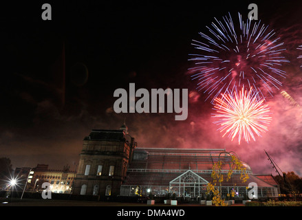 Fuochi d'artificio sopra il Palazzo del Popolo e giardini invernali nel verde di Glasgow, Scozia Foto Stock