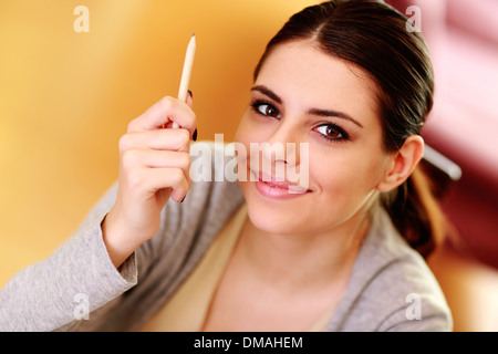 Closeup ritratto di una giovane donna sorridente tenendo una matita a casa Foto Stock