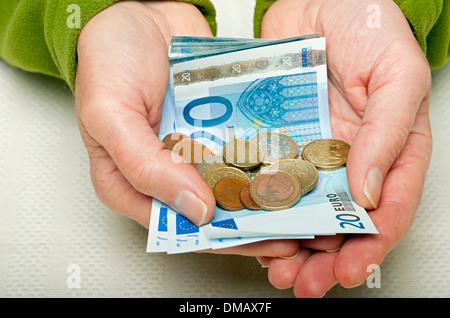 Primo piano mani uomo persona in possesso di 20 20 euro banconote e monete in contanti banconote banconote UE Europa europea Foto Stock