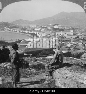 Due persone sedute in cima al colle guardando al porto e Macao, circa 1910 Foto Stock