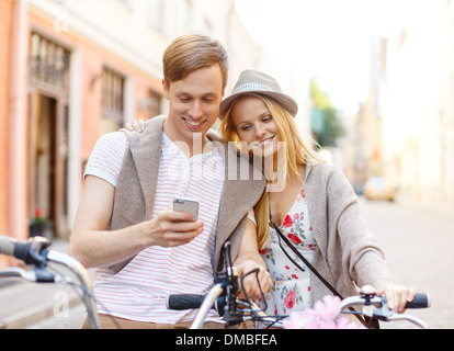 Giovane con lo smartphone e biciclette in città Foto Stock