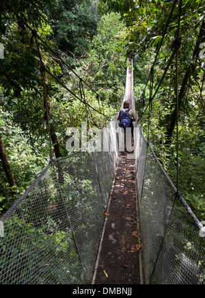 Una donna cammina lungo una delle passerelle sospese nella foresta a Rainmaker progetto di conservazione della Costa Rica. Foto Stock