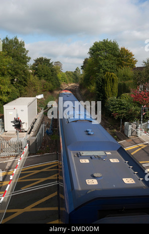 Il treno attraversa il livello crossing presso la stazione ferroviaria di Farnham, Surrey, Inghilterra, Regno Unito. Foto Stock