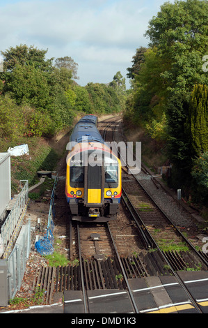 Il treno attraversa il livello crossing presso la stazione ferroviaria di Farnham, Surrey, Inghilterra, Regno Unito. Foto Stock