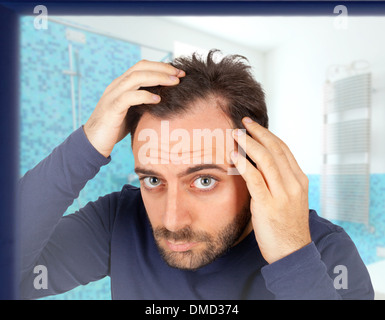Giovani caucasici uomo controlla la perdita di capelli nel bagno Foto Stock