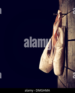 Vecchio usato rosa scarpe da ballo appesi su sfondo di legno Foto Stock