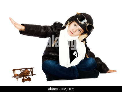 Felice ragazzo carino vestita come una guerra mondiale II riproduzione pilota con legno giocattolo aereo su sfondo bianco.look vintage Foto Stock