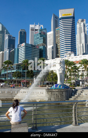 I TURISTI GUARDANDO LA SCULTURA MERLION, simboleggia la SINGAPORE, ai piedi dell'Ufficio Immobili nel quartiere finanziario, il quartiere centrale degli affari, SINGAPORE Foto Stock