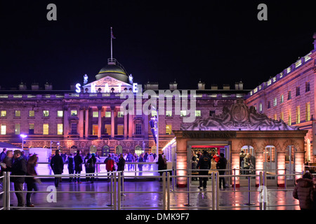 La gente guarda i pattinatori di ghiaccio Somerset House notte illuminata facciata di edificio storico intorno alla temporanea pista di pattinaggio invernale nel cortile Londra, Regno Unito Foto Stock
