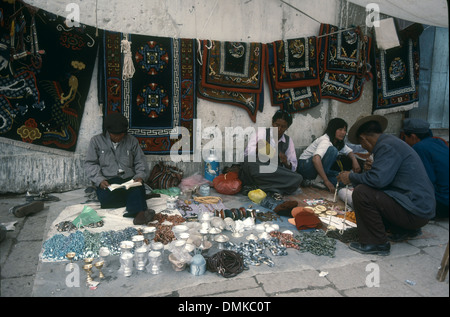 Venditori ambulanti vendono tappeti e di altra merce a Lhasa, in Tibet, in Cina. I clienti sono accovacciato davanti della merce. Foto Stock