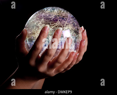 Mani tenendo un incandescente di vetro colorato o sfera di cristallo Foto Stock